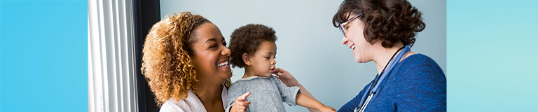 Woman doctor greeting mother and young daughter during office visit